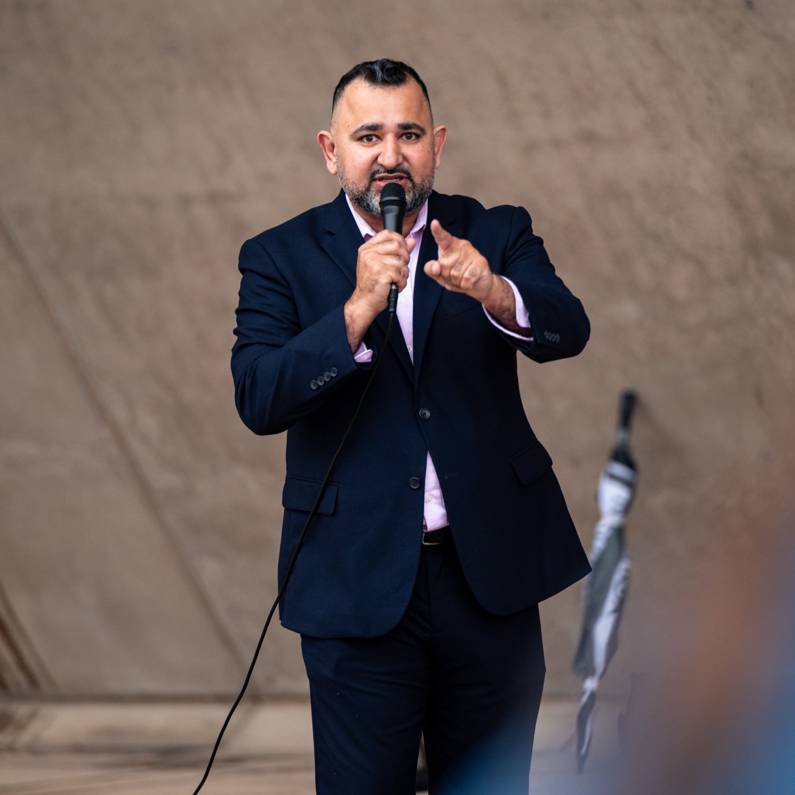 Zeeshan Hafeez speaking into a microphone at a rally